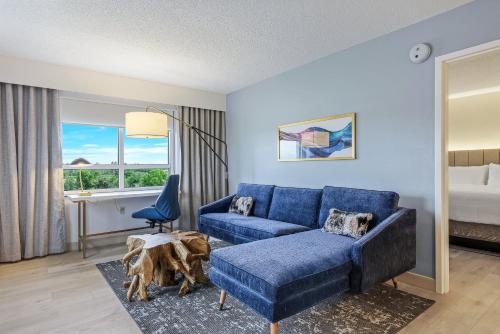 a living room with a blue couch and a bed at Crowne Plaza Ft Myers Gulf Coast by IHG in Fort Myers