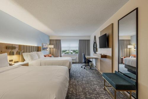 a hotel room with two beds and a desk at Crowne Plaza Ft Myers Gulf Coast by IHG in Fort Myers