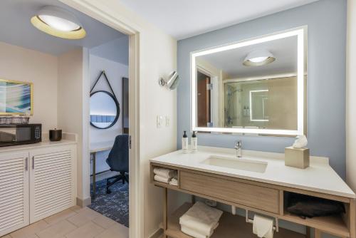 Crowne Plaza Ft Myers Gulf Coast, an IHG Hotel في فورت مايرز: حمام مع حوض ومرآة