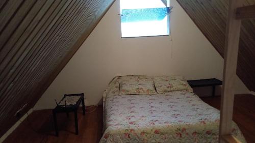 a small bedroom with a bed and a window at Chalé no morro in Ubatuba