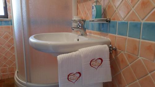 een badkamer met een wastafel en 2 handdoeken met harten erop bij Heart Of Sicily in Mistretta