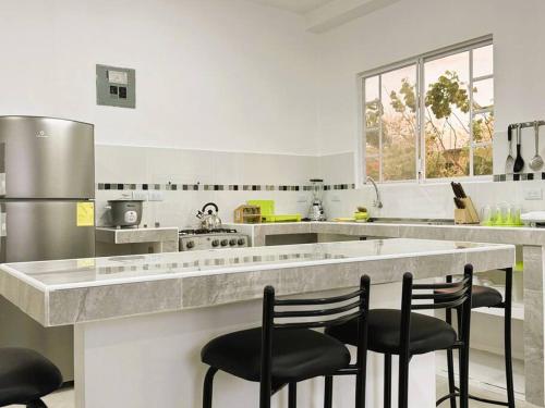 a kitchen with a large counter with four chairs at Hermoso apartamento por estrenar in Puerto Baquerizo Moreno