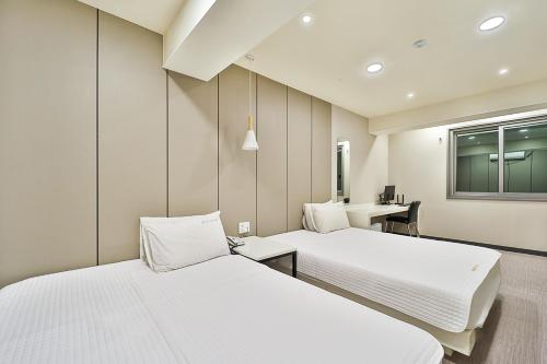 um quarto com 2 camas, uma secretária e uma janela em Top Motel Busan em Busan