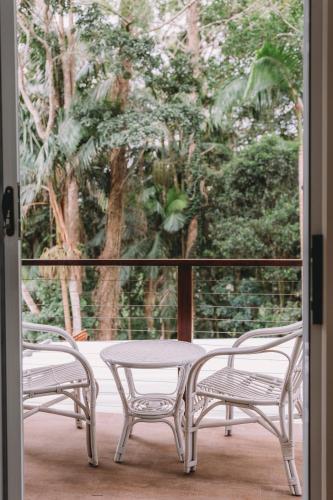 two chairs and a table on a porch with a window at TreeTops Tamborine Mountain in Mount Tamborine