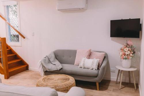 a living room with a couch and a flat screen tv at TreeTops Tamborine Mountain in Mount Tamborine