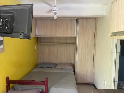 um quarto com uma cama e uma televisão na parede em Pousada - Quintal do Rosa na Praia do Rosa
