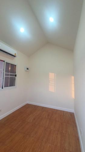 an empty living room with white walls and wooden floors at Family POOL VILLA CHAAM in Cha Am