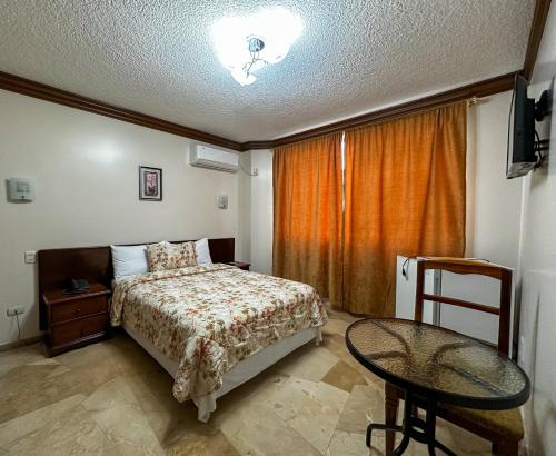 a bedroom with a bed and a table in it at Hotel Bucaneiro in Manta