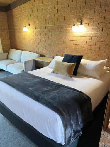 a large white bed in a room with a couch at Alexandra Motor Inn in Alexandra