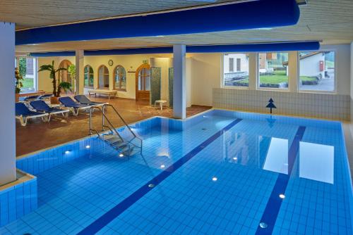 uma grande piscina com azulejos azuis num edifício em Hostellerie am Schwarzsee em Bad-Schwarzsee