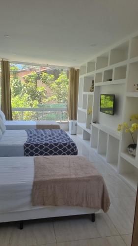 um quarto com uma cama grande e uma janela grande em Pousada MarÍsis Barra da Tijuca no Rio de Janeiro