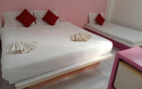 uma cama branca com almofadas vermelhas e brancas num quarto em lanta white sand beach guesthouse em Ban Mo Nae