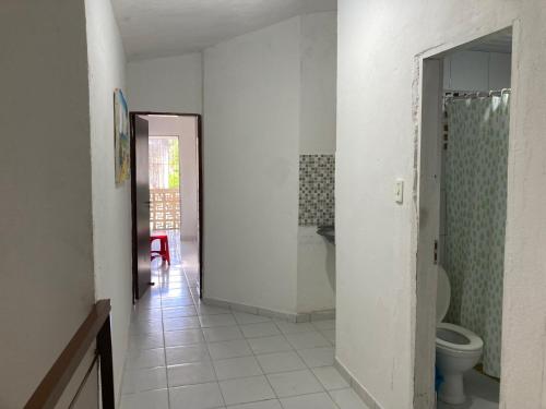 een witte badkamer met een toilet en een deuropening bij Casa Próxima ao Mar em Tamandaré - Seu refúgio a 20 m da praia in Tamandaré