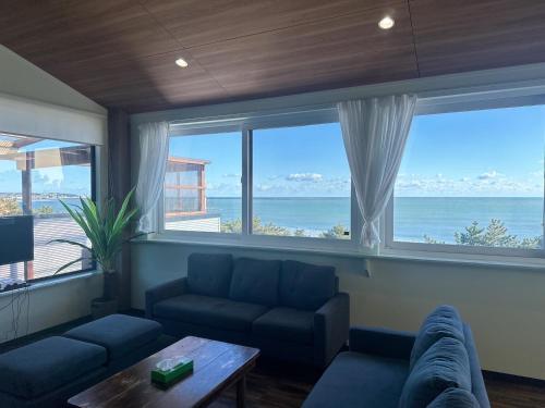 a living room with a couch and a view of the ocean at E Komo Mai 201号室 in Natsumi