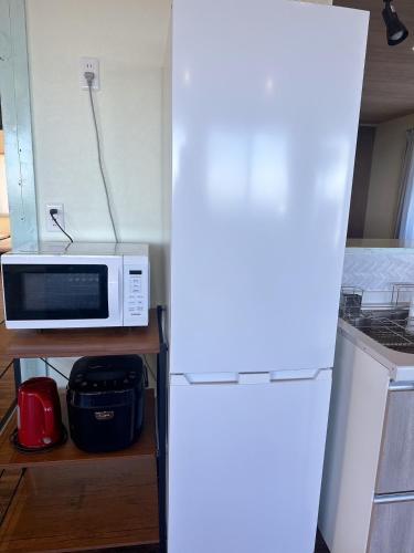 a white microwave sitting on a shelf next to a refrigerator at E Komo Mai 201号室 in Natsumi