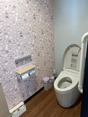 a bathroom with a toilet with a pink wallpaper at E Komo Mai 201号室 in Natsumi