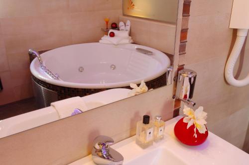 a bathroom with a tub and a sink with a mirror at Olympic Fashion Hotels in Athens