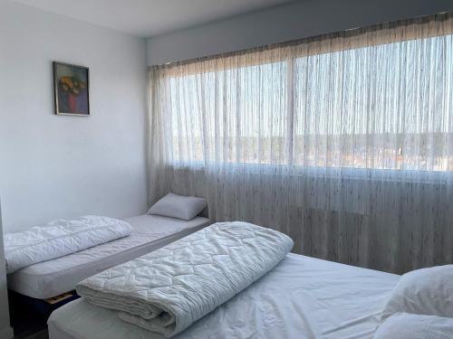 3 lits dans une chambre avec fenêtre et publicité dans l'établissement Magnifique appart rénové 2 chambres, face à la mer - 3 étoiles, garage privé, proche plage et commerces - FR-1-323-329, à Saint-Jean-de-Monts