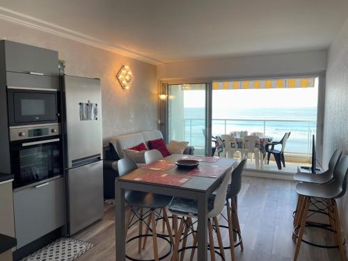 - une cuisine et une salle à manger avec une table et une vue sur l'océan dans l'établissement Magnifique appart rénové 2 chambres, face à la mer - 3 étoiles, garage privé, proche plage et commerces - FR-1-323-329, à Saint-Jean-de-Monts