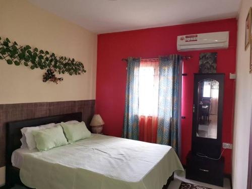 - une chambre avec un lit et un mur rouge dans l'établissement Red Lory residences apartment G1, à Pereybere