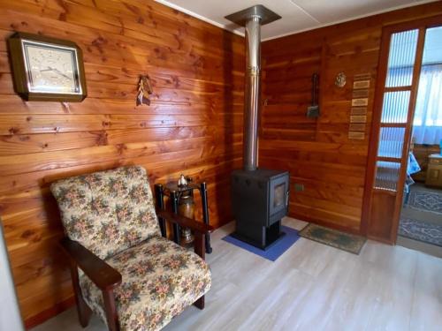 a living room with a stove and a chair at Casa acogedora en hermoso entorno Chiloe in Rauco