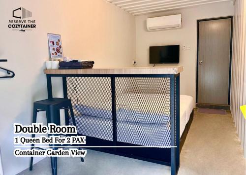 Habitación con cama, mesa y TV. en Reserve The Cozytainer, en Taiping