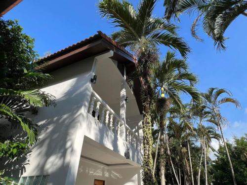 a white house with palm trees in front of it at Charming Villa Suite with Balcony near Beach in Patong Beach