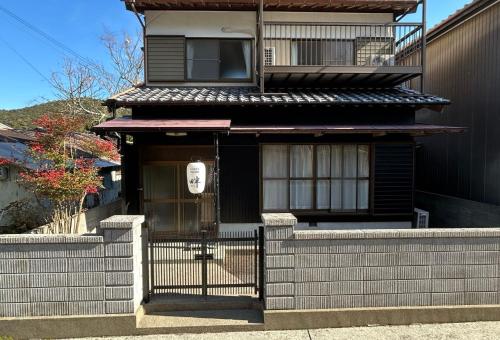 a black house with a gate and a fence at ゲストハウス 畔（hotori） in Nishimukai