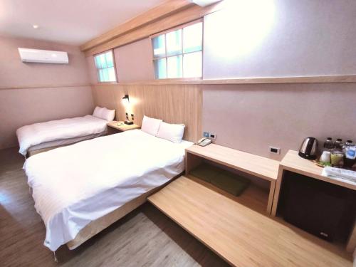 een hotelkamer met 2 bedden en een bureau bij AOIKE Hot Spring Hotel in Jiaoxi