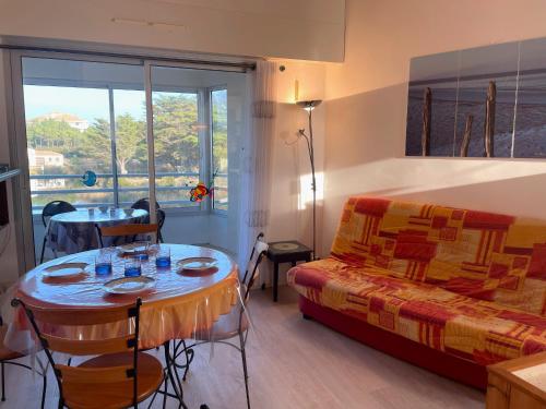 Cette chambre comprend une table, un lit et une fenêtre. dans l'établissement Appartement avec Mezzanine et Parking Privé - Proche Plage et Golf - FR-1-323-321, à Saint-Jean-de-Monts