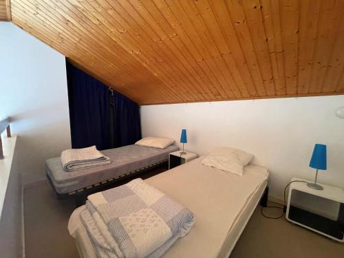 deux lits dans une chambre avec un plafond en bois dans l'établissement Appartement avec Mezzanine et Parking Privé - Proche Plage et Golf - FR-1-323-321, à Saint-Jean-de-Monts