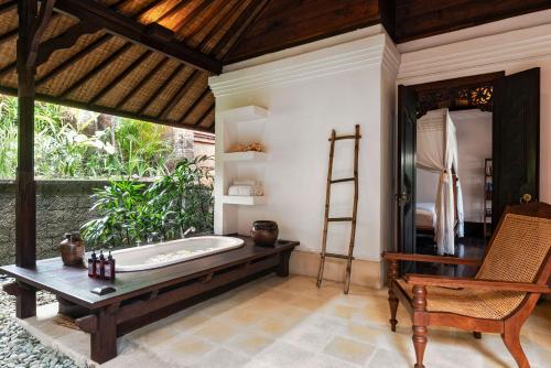 a bathroom with a tub and a chair and a table at Villa Pangi Gita in Canggu