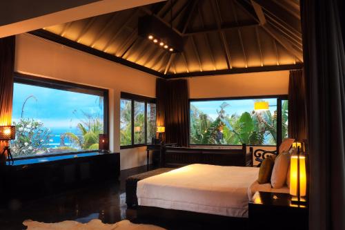 a bedroom with a bed and large windows at Villa Florimar - 50m to Seseh Beach in Canggu