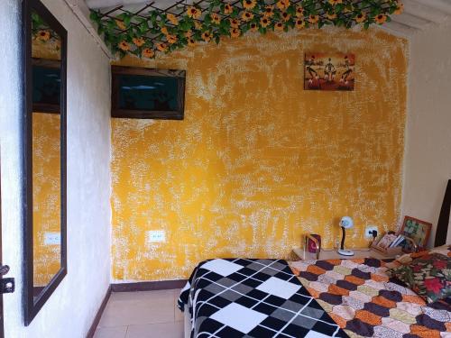 a bedroom with a yellow wall and a bed with a checkered blanket at Cabaña en el Campo in La Vega