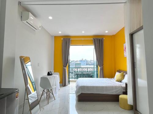 a bedroom with yellow walls and a bed and a table at Luxury Condotel Sai Gon 3 in Ho Chi Minh City