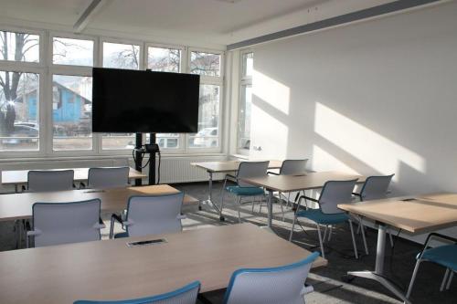 a classroom with tables and chairs and a flat screen tv at Akcent hotel in Prague