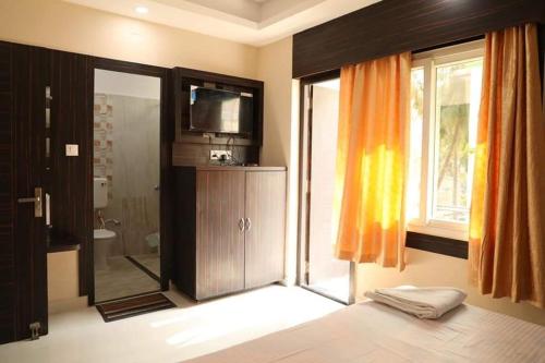 a bathroom with a shower and a television in a room at Hotel Sagar Kanya INN in Puri