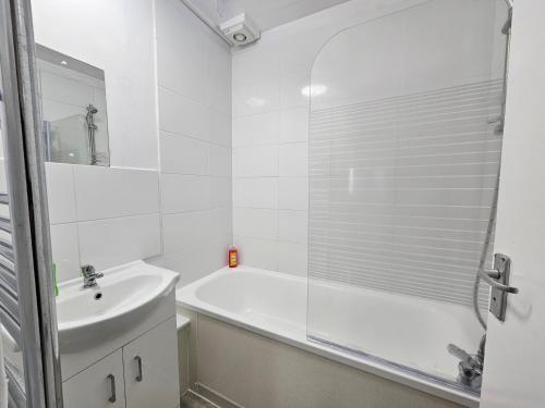 a white bathroom with a tub and a sink at Apartment Near Towerbridge in London
