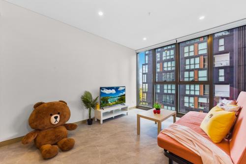 un grand ours en peluche assis dans un salon dans l'établissement 1Br Apt by Train&Shopping Pool&Gym with Water View, à Sydney