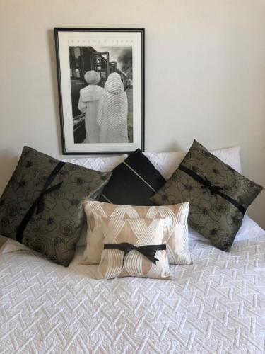 a bed with four pillows and a picture on the wall at Ponsonby Boutique Villa with Private Gym in Auckland