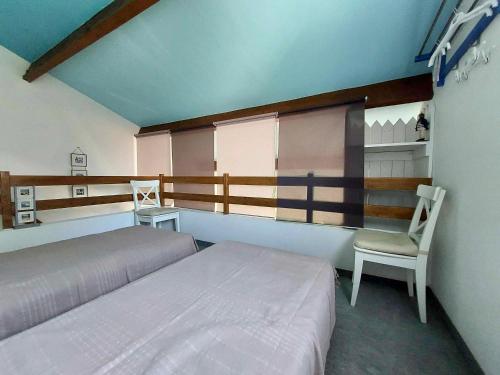 une chambre avec deux lits et une chaise dans l'établissement Maison avec piscine, tennis et aire de jeux à 950m de la plage de sable fin - Saint-Vincent-sur-Jard - FR-1-336-145, à Saint-Vincent-sur-Jard