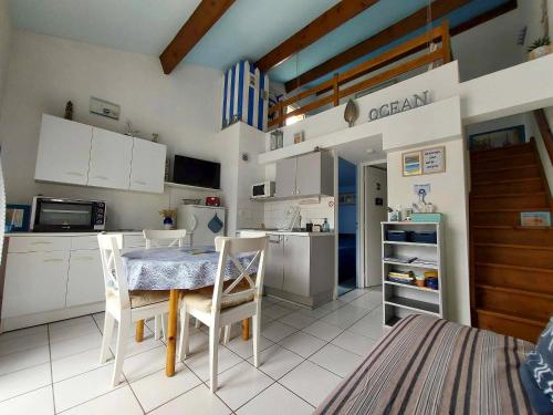 une cuisine avec des armoires blanches et une table et des chaises dans l'établissement Maison avec piscine, tennis et aire de jeux à 950m de la plage de sable fin - Saint-Vincent-sur-Jard - FR-1-336-145, à Saint-Vincent-sur-Jard