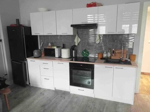 a kitchen with white cabinets and a black refrigerator at Odra River Condo in Szczecin