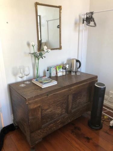 a wooden table with a mirror and a vase of flowers at Ponsonby Boutique Villa with Private Gym in Auckland