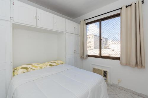 um quarto branco com uma cama e uma janela em Flat Posto 6 com Piscina - Copacabana no Rio de Janeiro