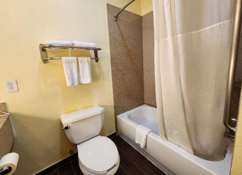 a bathroom with a white toilet and a shower at Days Inn & Suites by Wyndham Pasadena in Pasadena
