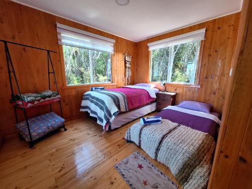 two beds in a room with wooden walls at Refugio cabañas Bosquemar 2 in Queilén
