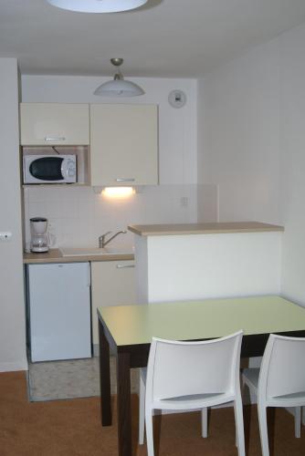 a kitchen with a table and two white chairs at Adonis Hauts De Honfleur in Équemauville