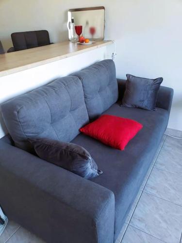 - un canapé bleu avec 2 oreillers rouges dans l'établissement Studio en Résidence Piscine Tennis, à Villeneuve-Loubet