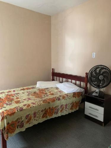 Schlafzimmer mit einem Bett und einem Schreibtisch mit einem Ventilator in der Unterkunft Casa bem localizada Cidreira in Cidreira